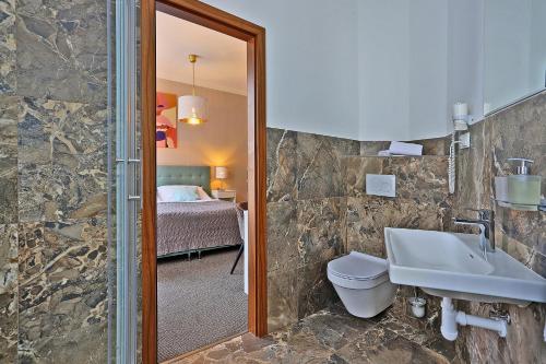 a bathroom with a sink and a toilet and a bed at Hotel Pilgrim in Karlovy Vary