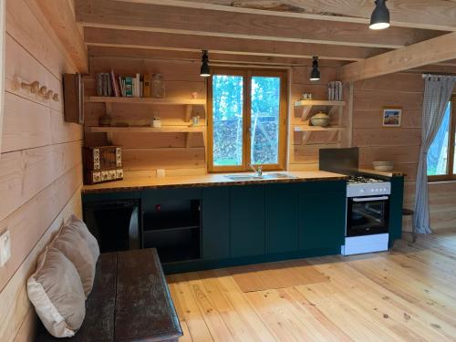 une cuisine dans une cabane en rondins avec un évier et une cuisinière dans l'établissement Les Cabanes de Lou-loup écologiques et autonomes, à Anzème