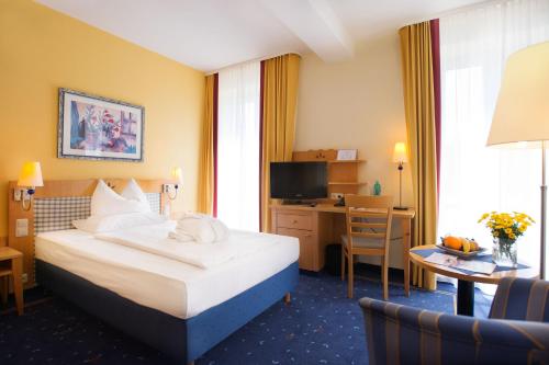 a hotel room with a bed and a desk at H+ Hotel & SPA Friedrichroda in Friedrichroda