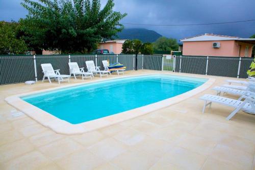 Una gran piscina con sillas y una mesa. en Locations l'Inzecca, en Ghisonaccia