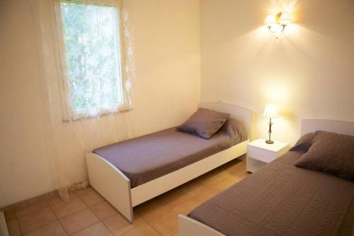 Un dormitorio con dos camas y una ventana. en Locations l'Inzecca, en Ghisonaccia