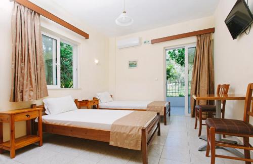 a room with a bed, chair, table and a window at Hotel Loula Rooms and Apartments in Kamena Vourla