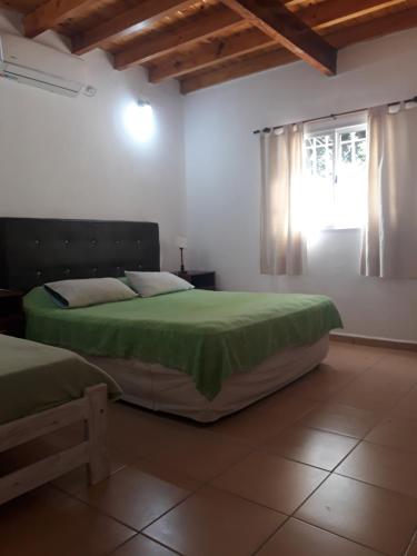 een slaapkamer met een groen bed en een raam bij Hermosa Casita Paso Patria in Paso de la Patria