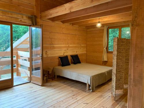 une chambre avec un lit dans une cabane en bois dans l'établissement Les Cabanes de Lou-loup écologiques et autonomes, à Anzème