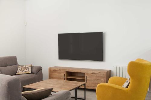 a living room with a couch and a tv on a wall at Villa Conchin Casa junto a Parque Natural in Alberique