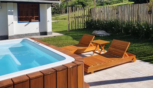 two chairs and a table next to a swimming pool at A Casinha Lumiar in Lumiar