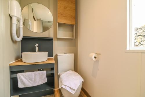 een badkamer met een wastafel, een toilet en een spiegel bij Azor'Oasis in Calhetas