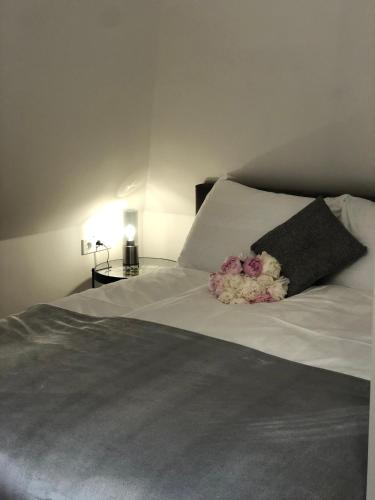 a bed with a black pillow and flowers on it at Duna P'Art Panzió in Verőce