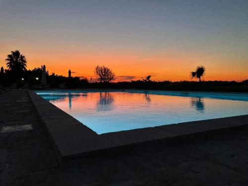 a swimming pool with a sunset in the background at B&B Terre dì Montecoco in San Pancrazio Salentino