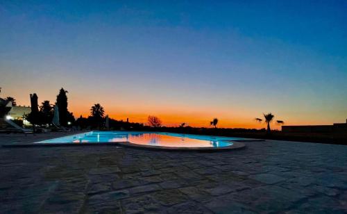 a swimming pool with a sunset in the background at B&B Terre dì Montecoco in San Pancrazio Salentino