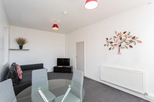 uma sala de estar com uma mesa de vidro e cadeiras em Cherry Property - Mulberry Suite em Blackpool