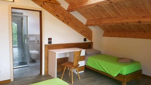 - une chambre mansardée avec un bureau et un lit dans l'établissement Camping Canè in Fiore, à Baselga di Pinè