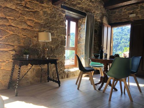 a room with a table and chairs in a stone wall at Ecolagar O Barqueiro in Pantón