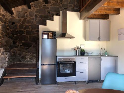 a kitchen with stainless steel appliances and a stone wall at Ecolagar O Barqueiro in Pantón