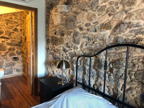 a bedroom with a stone wall with a bed and a lamp at Ecolagar O Barqueiro in Pantón