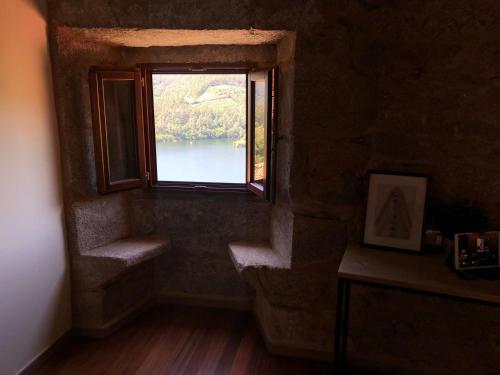 a room with a window with a view of a lake at Ecolagar O Barqueiro in Pantón