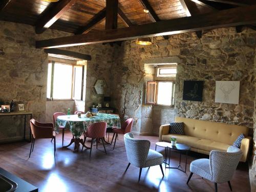 a living room with a couch and a table and chairs at Ecolagar O Barqueiro in Pantón