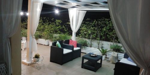 a patio with a couch and a table and curtains at Villetta Dote in Casarano