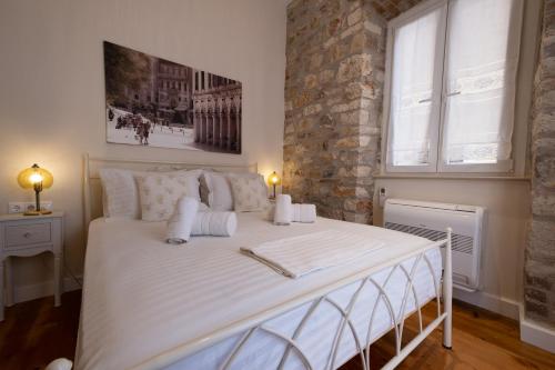 a bedroom with a large white bed with a brick wall at La Cantada - Renovated apartment in Corfu town in Corfu
