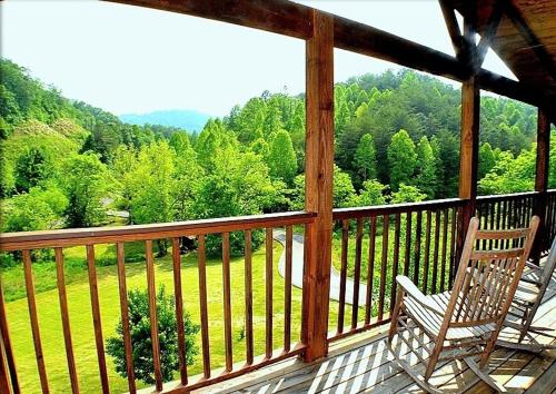 porche con 2 sillas y vistas a un campo en The Ranch Cabin in Great Smoky Mountain, en Sevierville