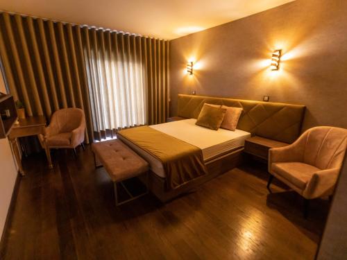 a hotel room with a bed and two chairs at Golden Mirror in Lamego