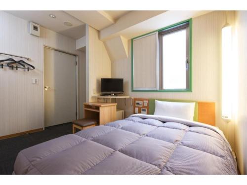 1 Schlafzimmer mit 2 Betten, einem Schreibtisch und einem Fenster in der Unterkunft R&B Hotel Kobe Motomachi - Vacation STAY 40715v in Kōbe