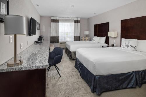 a hotel room with two beds and a desk at Home Inn & Suites Yorkton in Yorkton