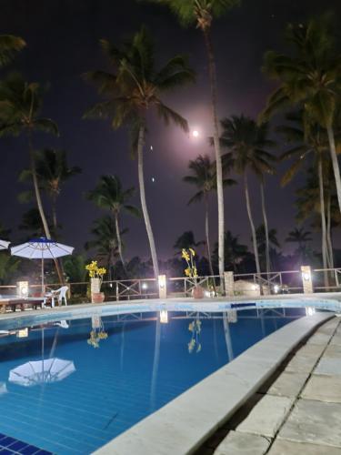 a swimming pool at night with palm trees at Chalé 17 - Porto do Sol - Pipa in Pipa