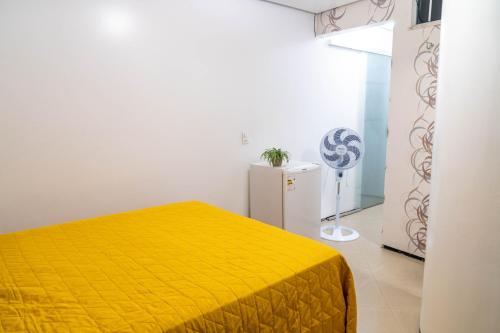 um quarto com uma cama amarela e um frigorífico em Flat da Vila em Viçosa do Ceará