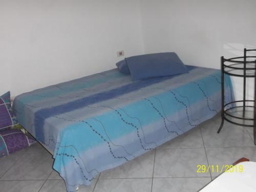 uma cama com um cobertor azul em cima em cantinho do sossego oficial em Caraguatatuba