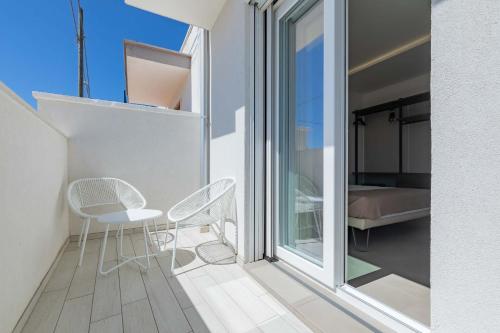 a balcony with two chairs and a table and a bed at Horizon rooms in Torre Lapillo