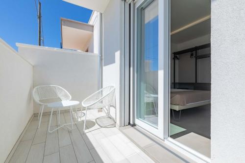 a balcony with two chairs and a table and a bed at Horizon rooms in Torre Lapillo