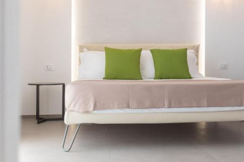 a white bed with two green pillows on it at Horizon rooms in Torre Lapillo