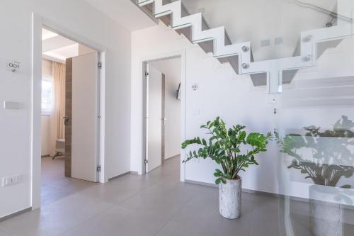 a white hallway with a staircase and a potted plant at Horizon rooms in Torre Lapillo