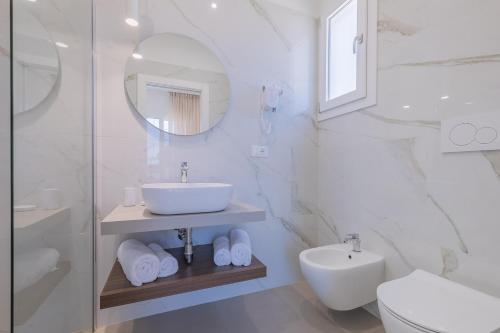 a white bathroom with a sink and a mirror at Horizon rooms in Torre Lapillo