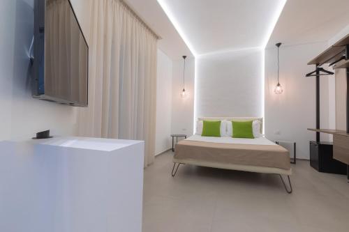 a bedroom with a bed with green pillows and a tv at Horizon rooms in Torre Lapillo
