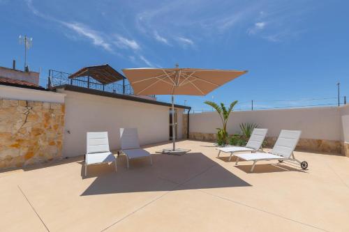 a group of chairs and an umbrella on a patio at Horizon rooms in Torre Lapillo