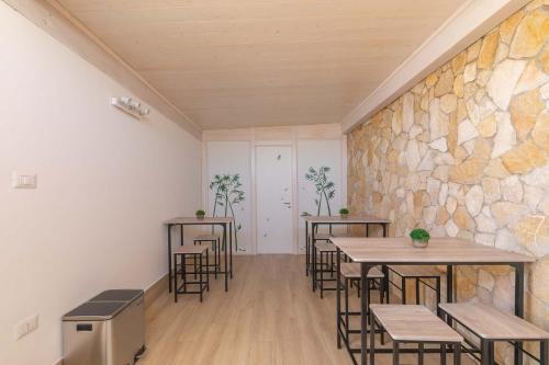 a room with tables and chairs and a stone wall at Horizon rooms in Torre Lapillo