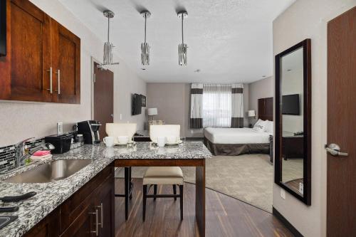 a kitchen with a sink and a room with a bed at Home Inn & Suites Yorkton in Yorkton