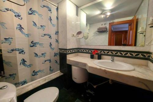 une salle de bain avec un lavabo, des toilettes et un miroir dans l'établissement Amplio apartamento en la playa del Esquinzo, à Playa Jandía