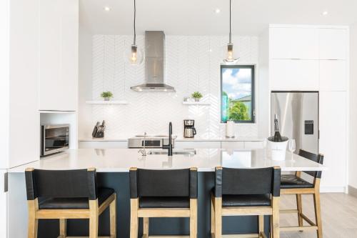 a kitchen with a large kitchen island with black chairs at H2O LifeStyle Resort in Long Bay Hills