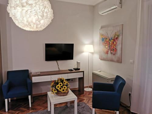 a living room with two blue chairs and a tv at Apartman Jovana 2 in Belgrade