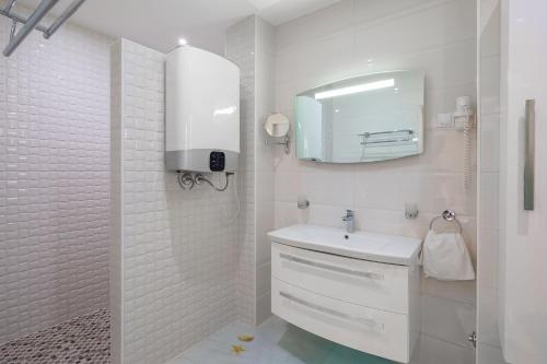 biała łazienka z umywalką i lustrem w obiekcie Appartements Banya w Korčuli