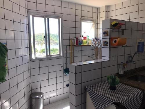 a white tiled bathroom with a table and a window at Apartamento a Beira Mar em Setiba Guarapari in Guarapari