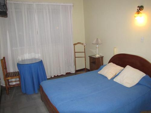 a bedroom with a blue bed and a window at Hotel Rio in Rancagua