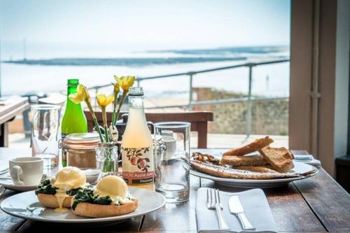 a table with plates of food and a view of the ocean at Stylish holiday let in central Broadstairs in Broadstairs