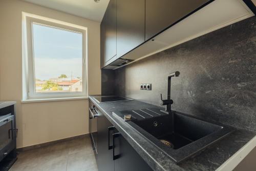 eine Küche mit einem schwarzen Waschbecken und einem Fenster in der Unterkunft Poorbaltics Apartments in Liepāja