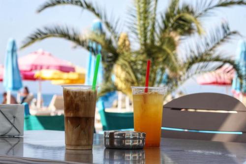 two drinks sitting on a table near a beach at Atlantis Atmosphere Apartment in Burgas City