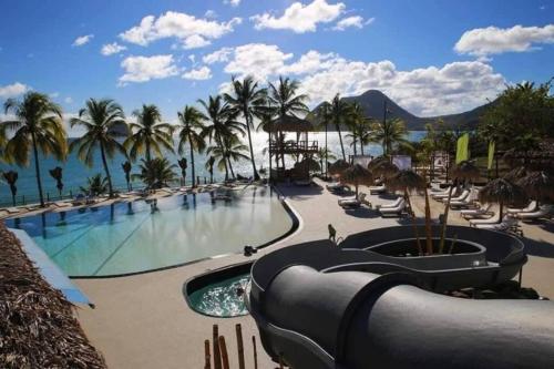 a resort with a swimming pool and palm trees at Blue Mine Home Studio in Le Diamant