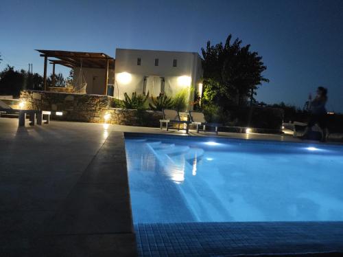 a swimming pool in front of a house at night at Andria's suites in Chrissi Akti
